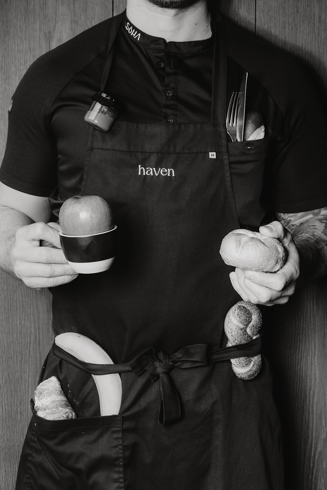Koch hält Tasse mit Apfel, Semmel und hat Besteck und Honig eingeschoben. Position als Frühstückskoch und Frühstückskellner in den Sôha Hotels