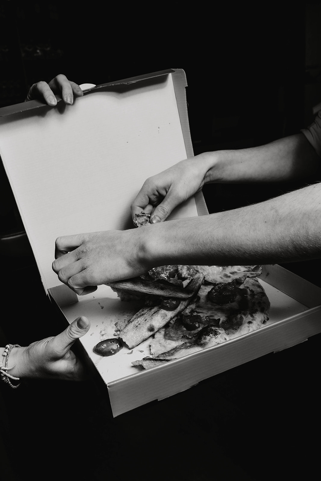 Männerhände zereissen eine Pizza vom deck7 der Sôha Hotels