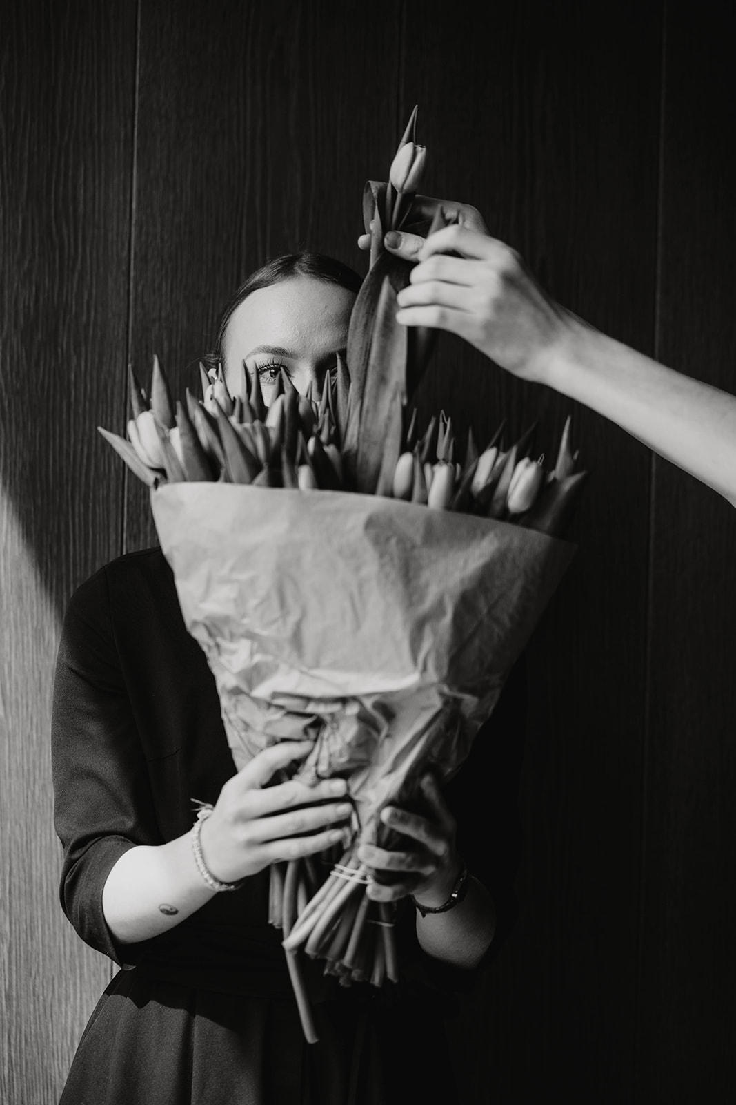 Frau hält einen Strauß Tulpen. Männerhände ziehen eine Tulpe raus.